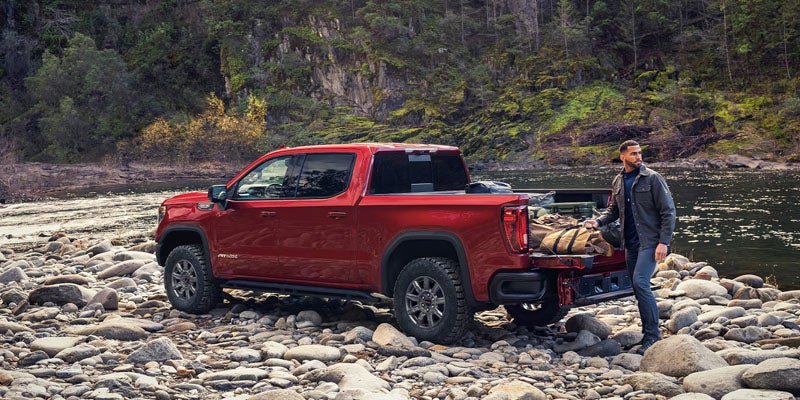 Red GMC Sierra 1500 pickup truck parked on a rocky riverbank