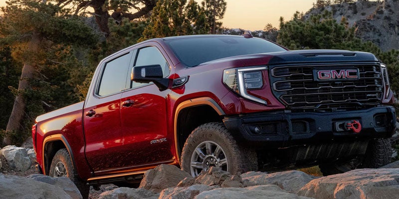Red GMC Sierra 1500 pickup truck driving over rocky terrain